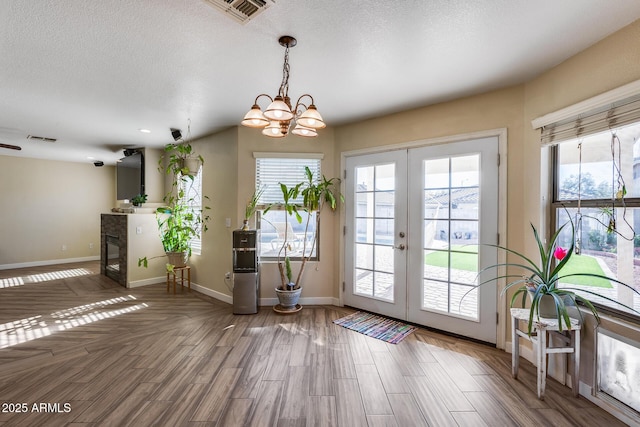 entryway featuring a notable chandelier, hardwood / wood-style flooring, french doors, and a healthy amount of sunlight