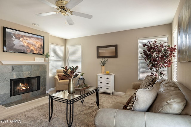 living room featuring ceiling fan, a tile fireplace, a wealth of natural light, and light hardwood / wood-style flooring