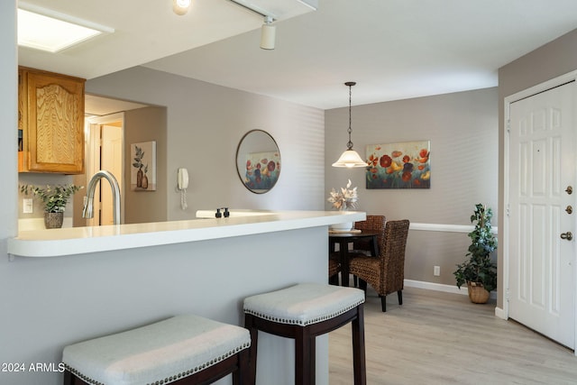 kitchen with pendant lighting, kitchen peninsula, sink, and light hardwood / wood-style flooring