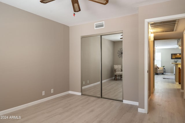 unfurnished bedroom with ceiling fan, a closet, and light hardwood / wood-style floors