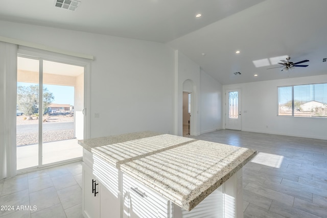 kitchen with white cabinets, ceiling fan, a center island, and lofted ceiling