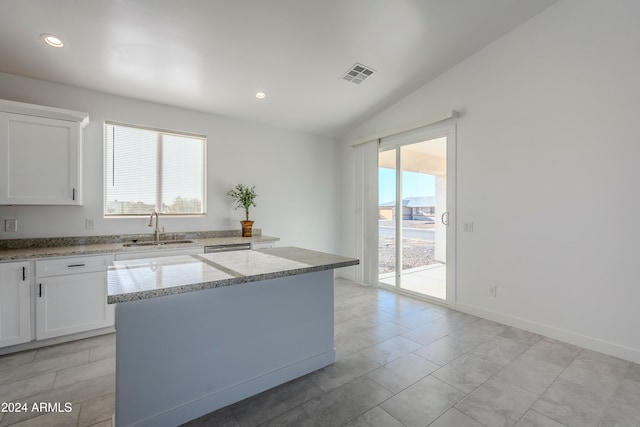 kitchen with a kitchen island, white cabinetry, sink, and vaulted ceiling