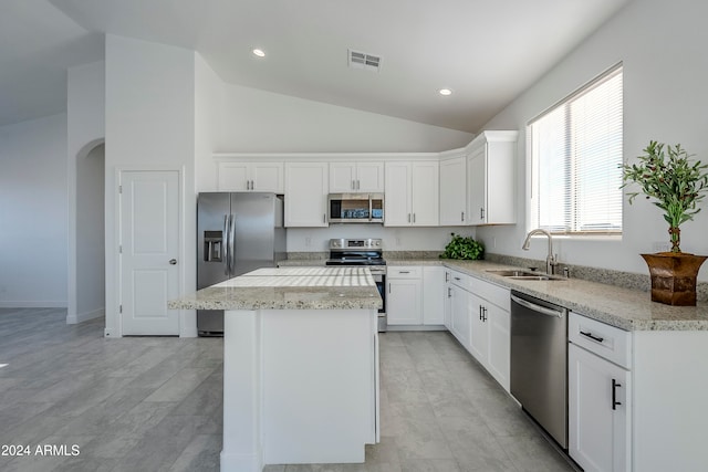 kitchen featuring white cabinetry, sink, a center island, light stone counters, and appliances with stainless steel finishes