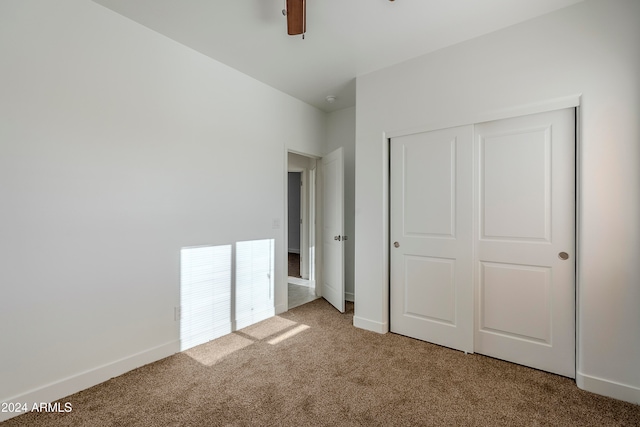 unfurnished bedroom featuring carpet, ceiling fan, and a closet