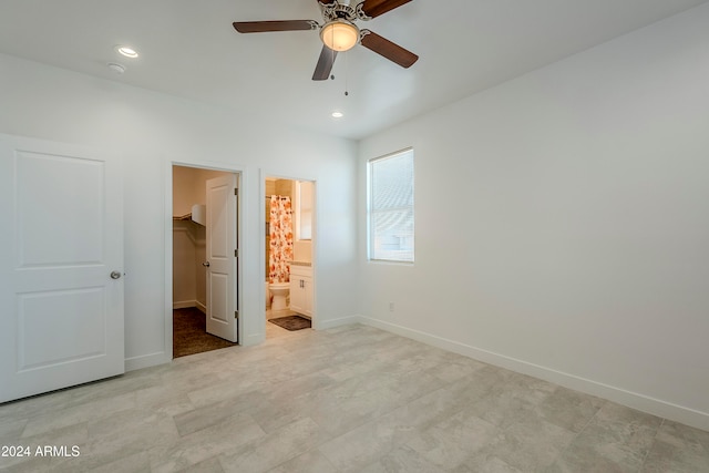 unfurnished bedroom featuring a walk in closet, connected bathroom, a closet, and ceiling fan