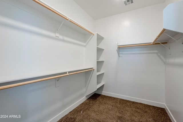 walk in closet featuring dark carpet