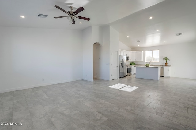 unfurnished living room with ceiling fan, sink, and high vaulted ceiling