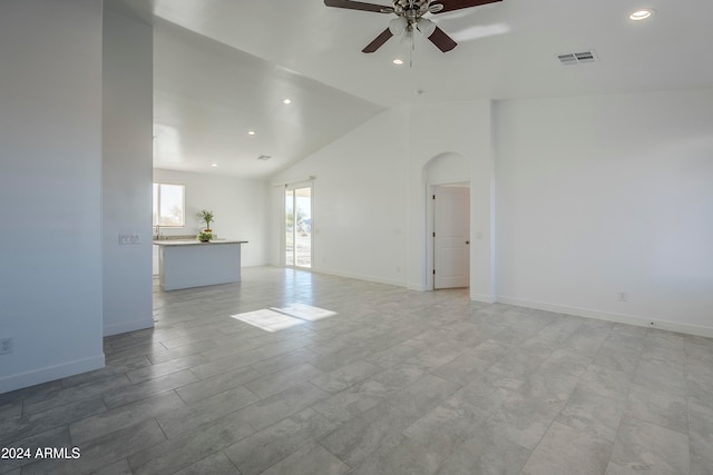 unfurnished living room featuring ceiling fan and high vaulted ceiling