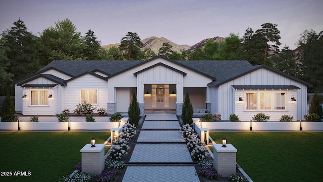 modern farmhouse style home featuring a front lawn, a mountain view, board and batten siding, and roof with shingles