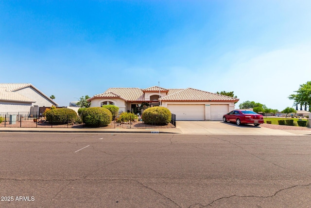 mediterranean / spanish-style home with a tiled roof, a garage, driveway, fence, and stucco siding