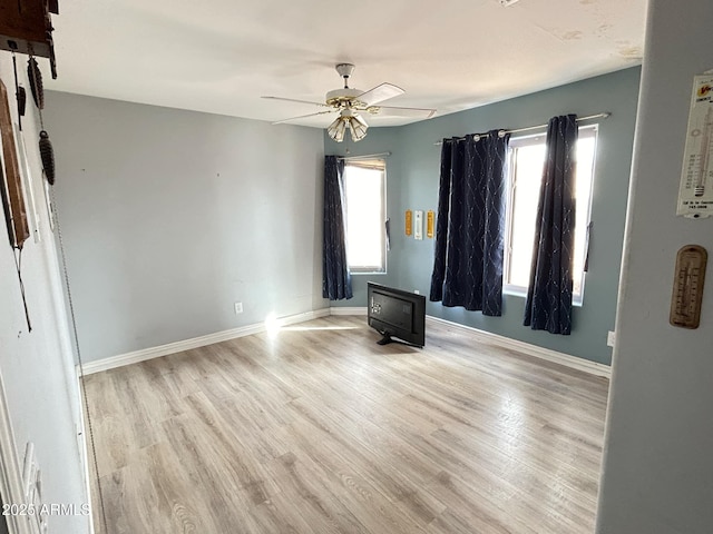 empty room with a ceiling fan, baseboards, and light wood finished floors