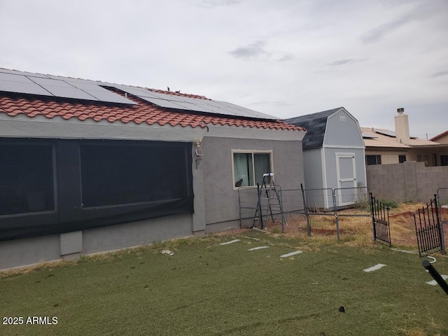 view of side of home featuring a yard, roof mounted solar panels, fence, and stucco siding