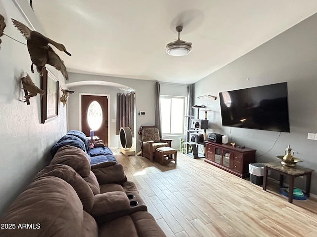 living room featuring arched walkways, vaulted ceiling, and wood finished floors