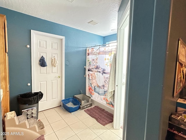 foyer entrance featuring visible vents, a textured ceiling, and light tile patterned floors