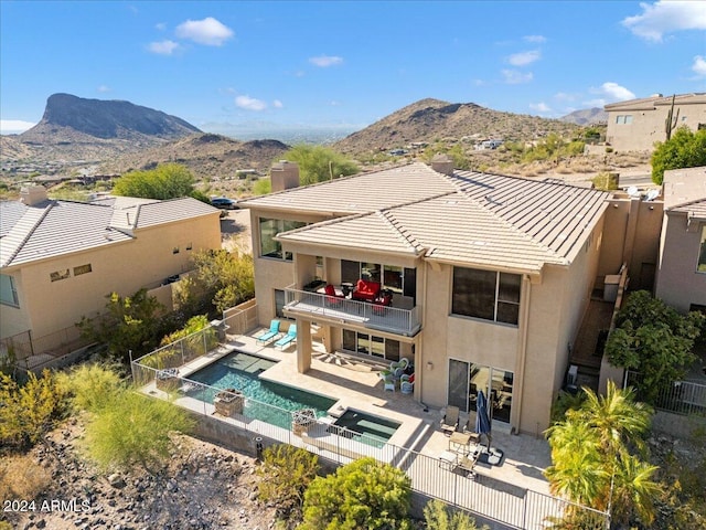 back of house with a mountain view, a balcony, a patio area, and a pool with hot tub