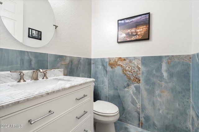 bathroom featuring vanity, tile walls, and toilet