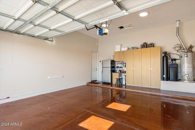 garage featuring stainless steel fridge, gas water heater, and a garage door opener