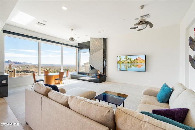 living room featuring ceiling fan, a mountain view, and light carpet