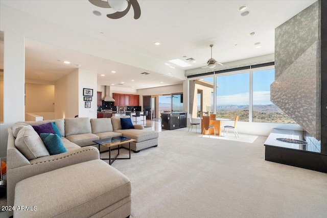 living room featuring ceiling fan, a mountain view, and light carpet