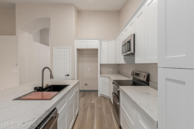 2189 E Ranch Ct, Gilbert, AZ 85296 - kitchen featuring appliances with stainless steel finishes, light wood finished floors, white cabinetry, a sink, and light stone countertops