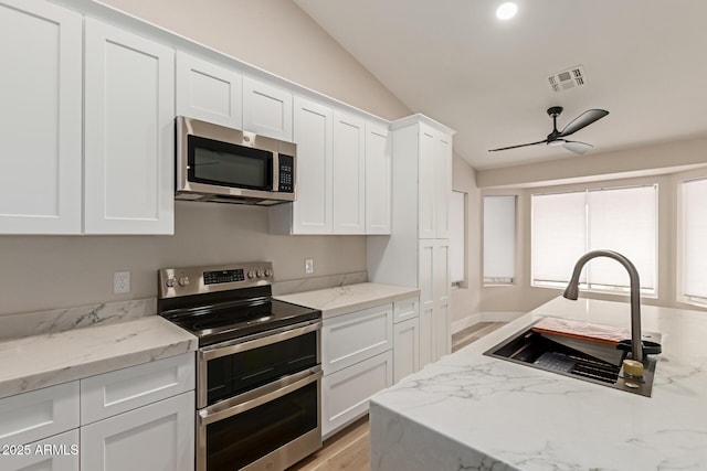 2189 E Ranch Ct, Gilbert, AZ 85296 - kitchen with stainless steel appliances, a sink, white cabinets, light wood-type flooring, and vaulted ceiling
