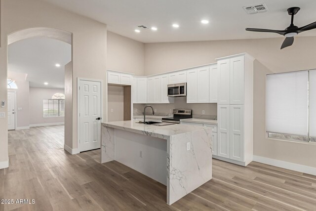 2189 E Ranch Ct, Gilbert, AZ 85296 - kitchen featuring appliances with stainless steel finishes, a sink, arched walkways, a ceiling fan, and light stone counters