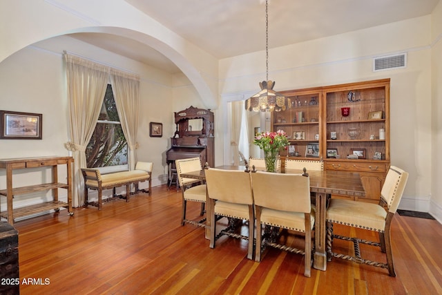 7252 N Central Ave, Phoenix, AZ 85020 - dining room featuring arched walkways, wood finished floors, a chandelier, and baseboards
