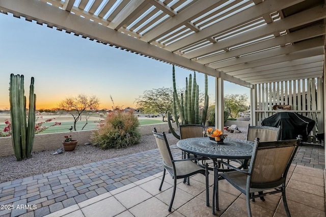 patio terrace at dusk featuring grilling area and a pergola