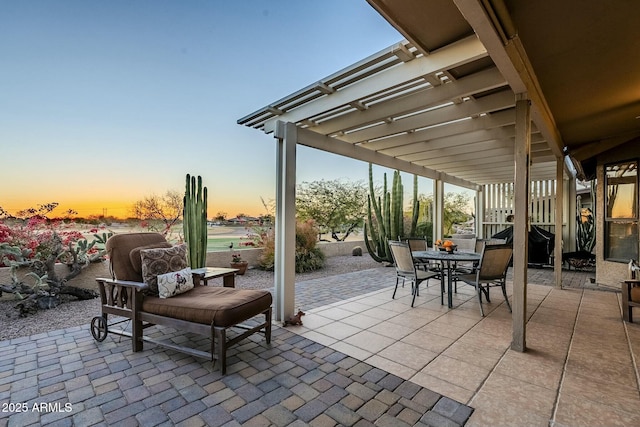 patio terrace at dusk with area for grilling and a pergola