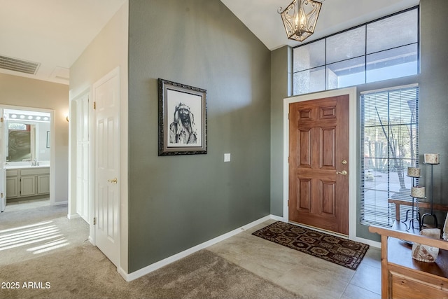 carpeted foyer entrance with sink, vaulted ceiling, and a chandelier