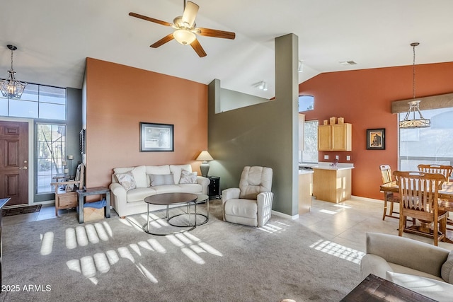 carpeted living room with ceiling fan with notable chandelier and high vaulted ceiling