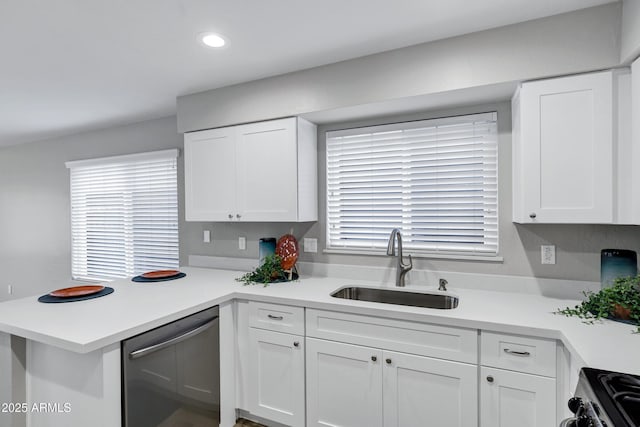 kitchen with a sink, appliances with stainless steel finishes, a peninsula, white cabinets, and light countertops