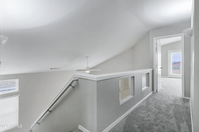 hallway with visible vents, carpet floors, baseboards, vaulted ceiling, and an upstairs landing