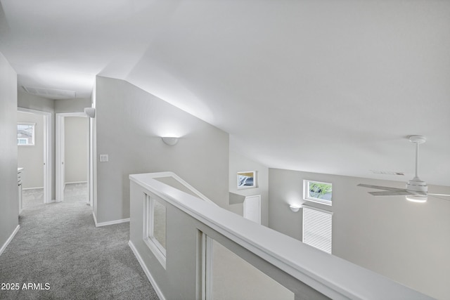 hall with carpet flooring, plenty of natural light, an upstairs landing, and baseboards