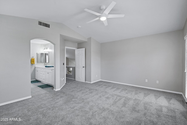 unfurnished bedroom featuring visible vents, baseboards, arched walkways, carpet, and lofted ceiling