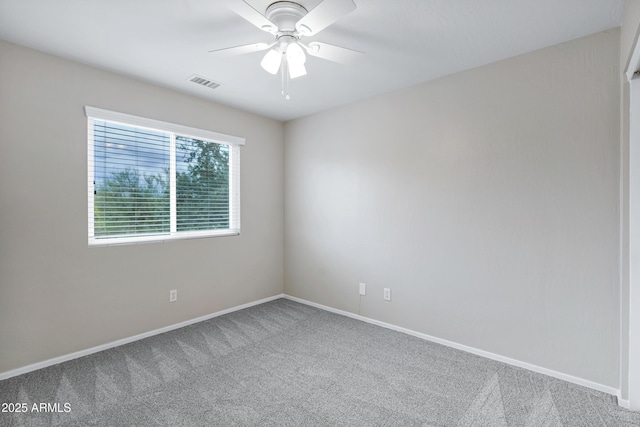 spare room featuring carpet flooring, a ceiling fan, visible vents, and baseboards