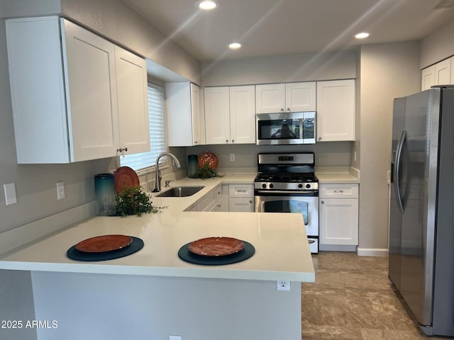 kitchen with white cabinetry, a peninsula, appliances with stainless steel finishes, and a sink