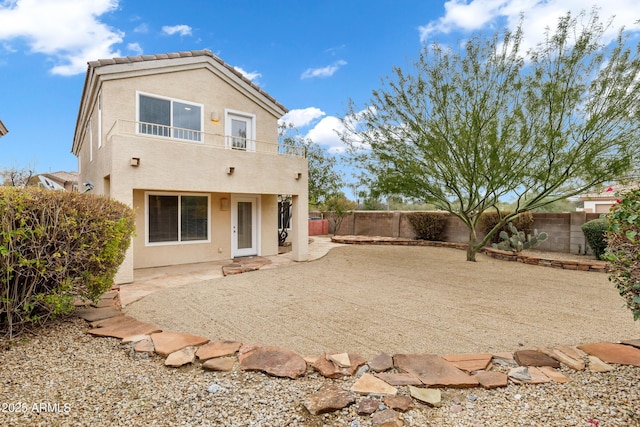 back of house featuring a tiled roof, stucco siding, a fenced backyard, a balcony, and a patio