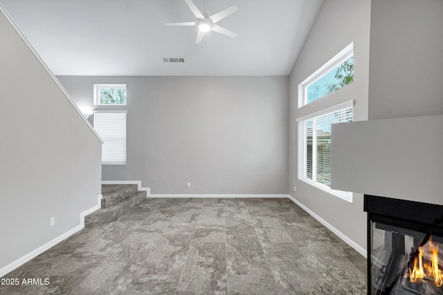 unfurnished living room with a wealth of natural light, visible vents, baseboards, and a ceiling fan