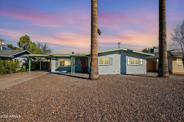 view of front of property with a carport, concrete block siding, and driveway