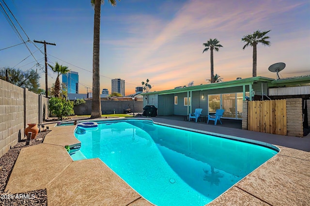 pool at dusk featuring a fenced backyard, a fenced in pool, and a patio