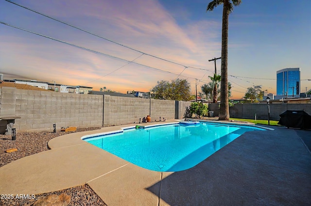 pool at dusk featuring a patio area, a fenced backyard, and a fenced in pool