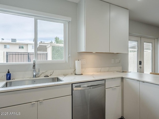 kitchen featuring dishwasher, a sink, healthy amount of natural light, and white cabinetry