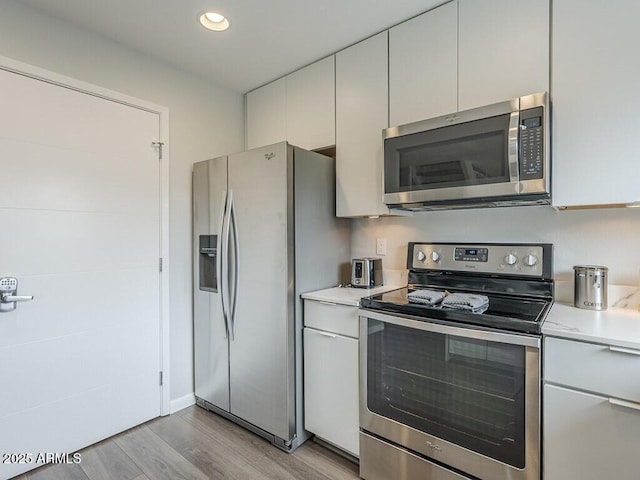 kitchen with stainless steel appliances, light countertops, light wood-type flooring, and recessed lighting