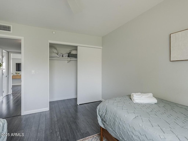 bedroom with dark wood-type flooring, a closet, and baseboards