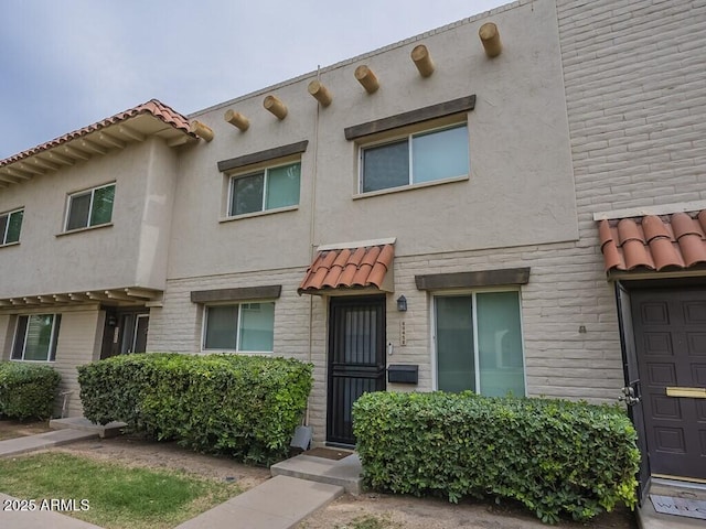 multi unit property with stucco siding and a tiled roof