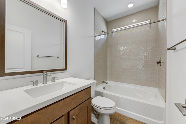 full bathroom with hardwood / wood-style floors, vanity, tiled shower / bath combo, and toilet