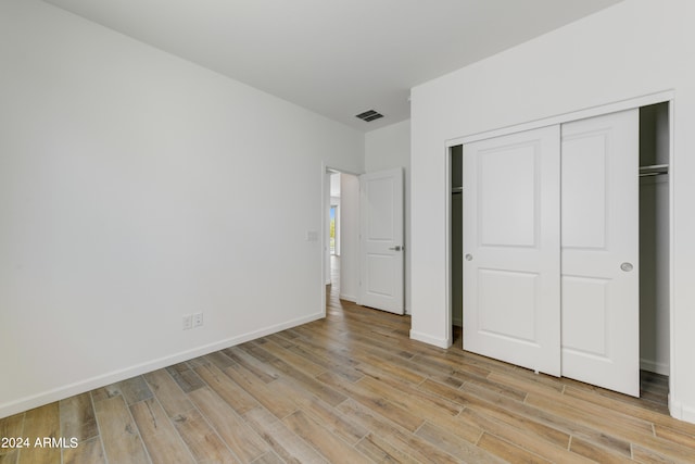 unfurnished bedroom featuring light hardwood / wood-style flooring and a closet