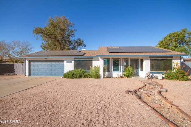 single story home featuring solar panels and a garage