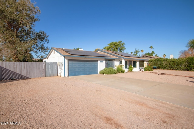 ranch-style home featuring solar panels and a garage